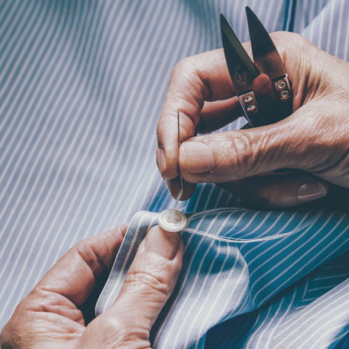 A mother-of-pearl button being attached to a shirt